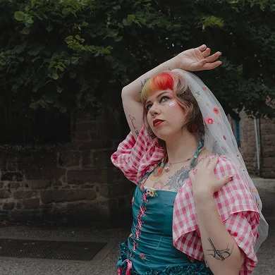 Tenue de mariée Anouchka. Zoom sur le corste à manches et le voile en tulle brodée de fleurs multicolores.