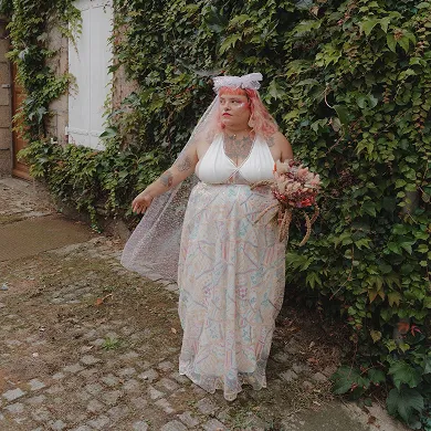 Robe de mariée Themis. Une robe très simple, ouverte dans le dos, décolleté, agrémentée d’une super dentelle à sequins colorés, ainsi que d’un voile à sequins colorés.